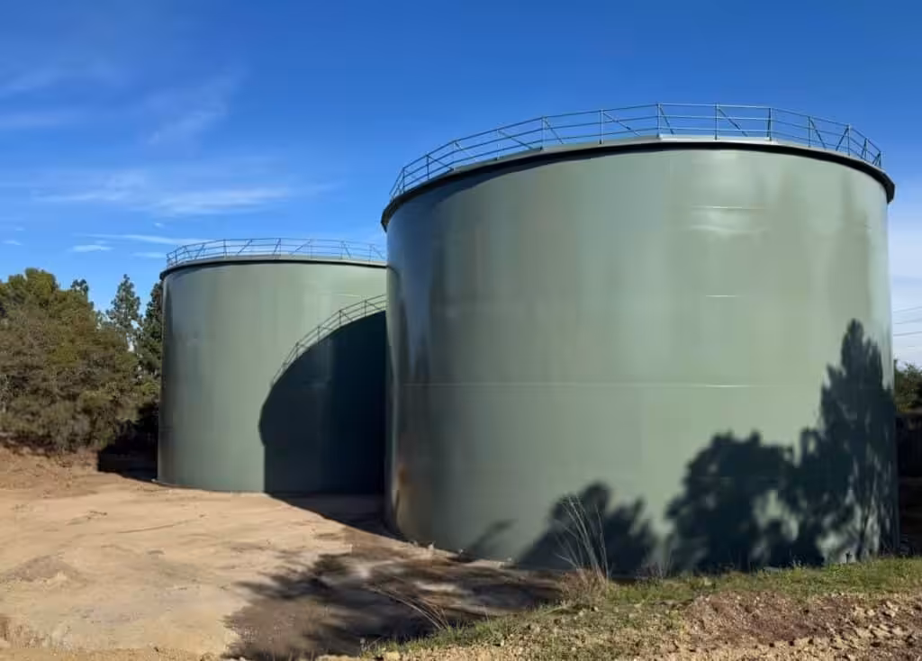 Two large green cylindrical tanks