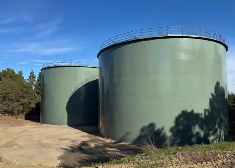 Two large green cylindrical tanks